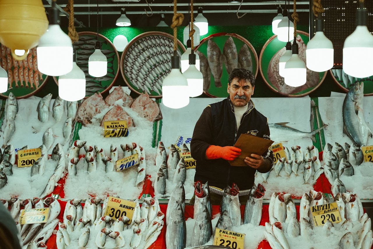Fishmonger in Ankara's market displaying fresh seafood under vibrant lighting.